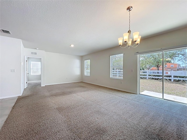 empty room with visible vents, a chandelier, and baseboards