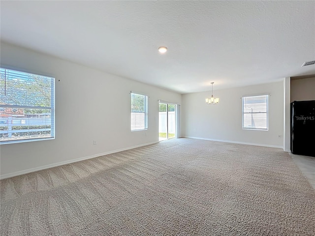 unfurnished living room featuring a chandelier, light carpet, and baseboards