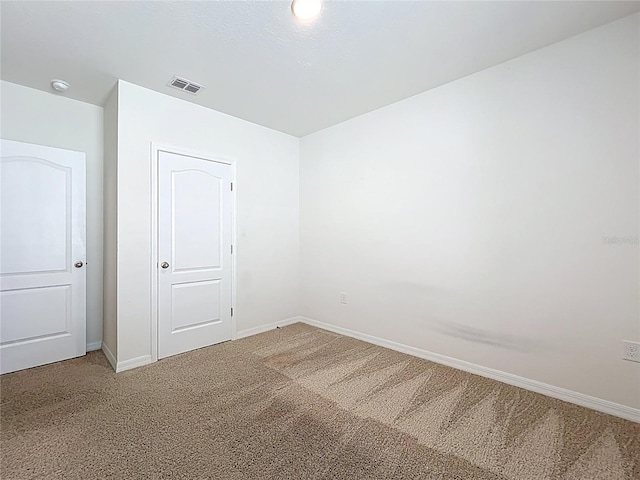 empty room featuring visible vents, light carpet, and baseboards