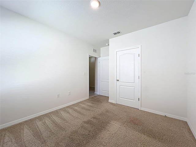 unfurnished bedroom featuring carpet flooring, visible vents, and baseboards