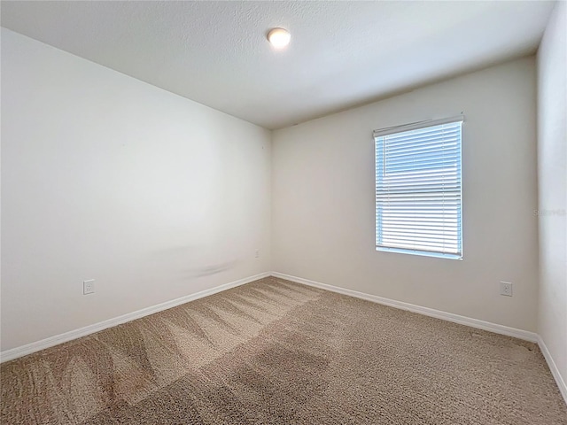 spare room featuring light carpet and baseboards