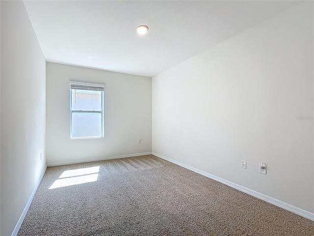 carpeted empty room featuring baseboards
