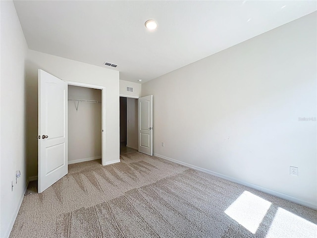 unfurnished bedroom with a closet, visible vents, light colored carpet, and baseboards