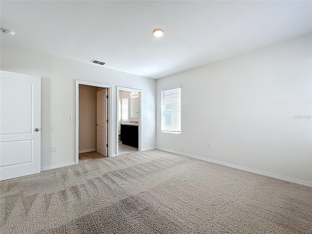 unfurnished bedroom with baseboards, visible vents, light carpet, and ensuite bath