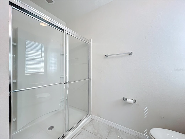 bathroom with baseboards, a stall shower, and toilet