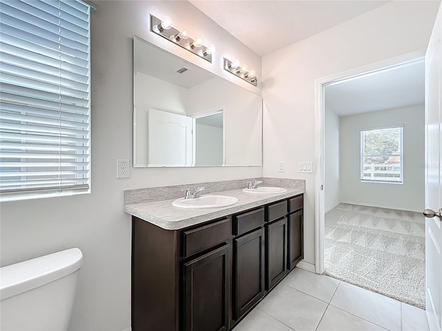 bathroom featuring toilet, tile patterned flooring, double vanity, and a sink