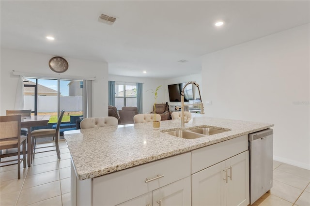 1535 Barberry Dr, Kissimmee, FL 34744 - kitchen with light stone counters, dishwasher, an island with sink, open floor plan, and visible vents