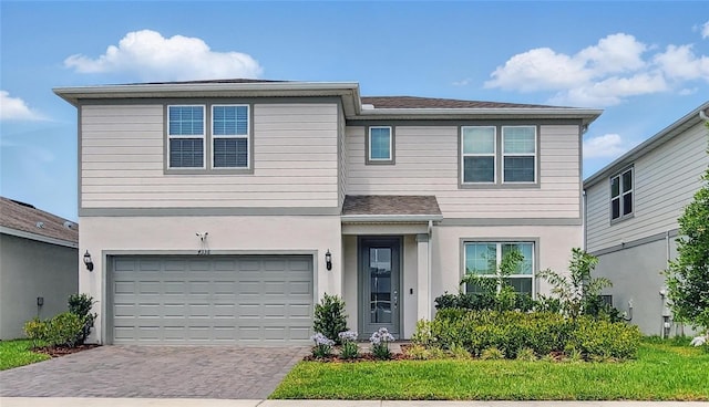 traditional-style home featuring decorative driveway, a garage, and stucco siding