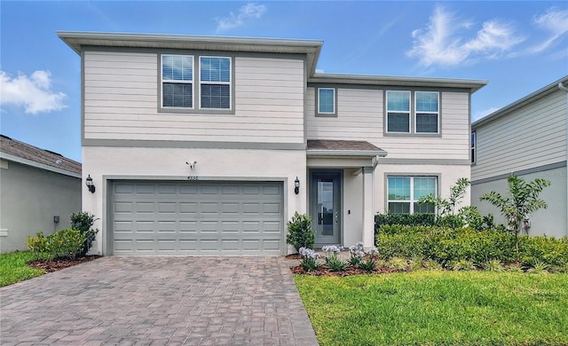 traditional-style home featuring stucco siding, an attached garage, decorative driveway, and a front yard