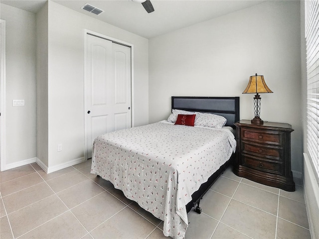 bedroom featuring ceiling fan, visible vents, light tile patterned floors, baseboards, and a closet