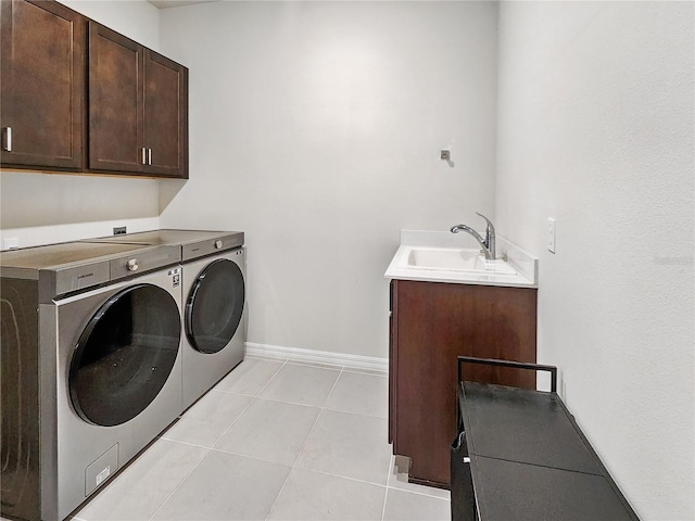 laundry room featuring light tile patterned flooring, baseboards, a sink, cabinet space, and independent washer and dryer