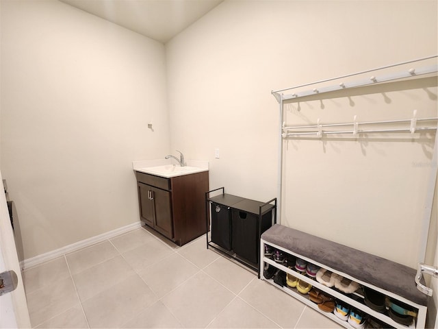clothes washing area featuring light tile patterned floors, baseboards, and a sink