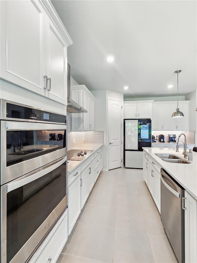 kitchen featuring light countertops, white cabinetry, a sink, appliances with stainless steel finishes, and decorative light fixtures