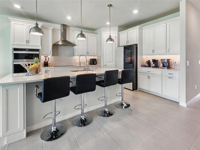 kitchen with decorative backsplash, smart refrigerator, double oven, and wall chimney exhaust hood