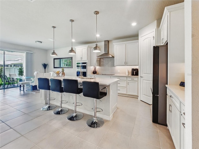 kitchen featuring appliances with stainless steel finishes, tasteful backsplash, light countertops, a breakfast bar, and wall chimney exhaust hood