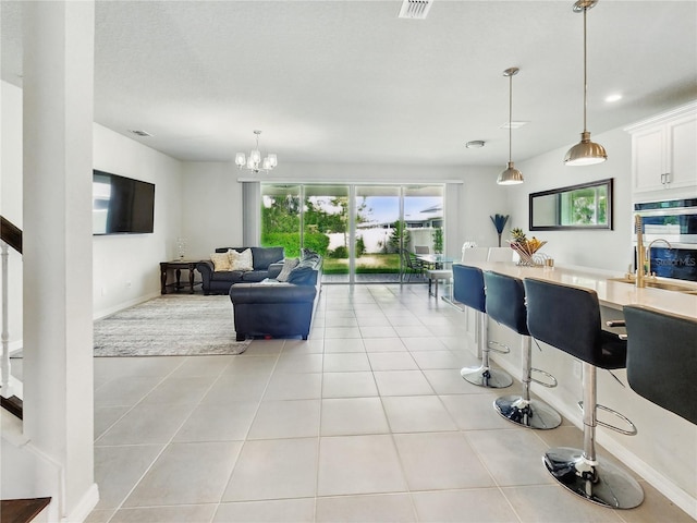 living area with light tile patterned floors, baseboards, visible vents, and a notable chandelier