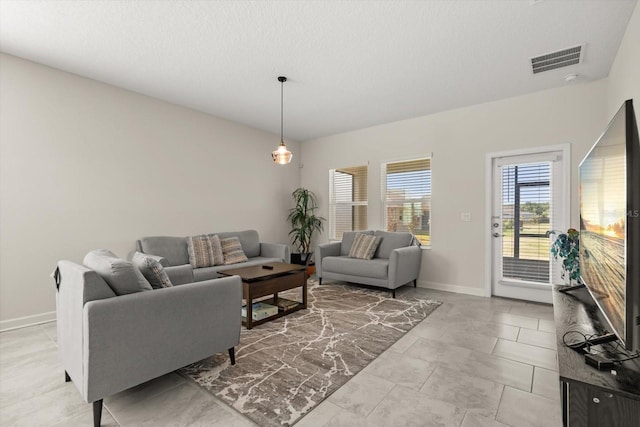 living room featuring a textured ceiling, visible vents, and baseboards