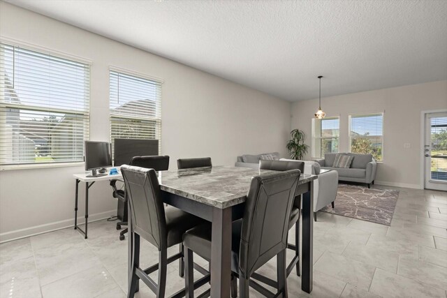 dining room with a textured ceiling and baseboards
