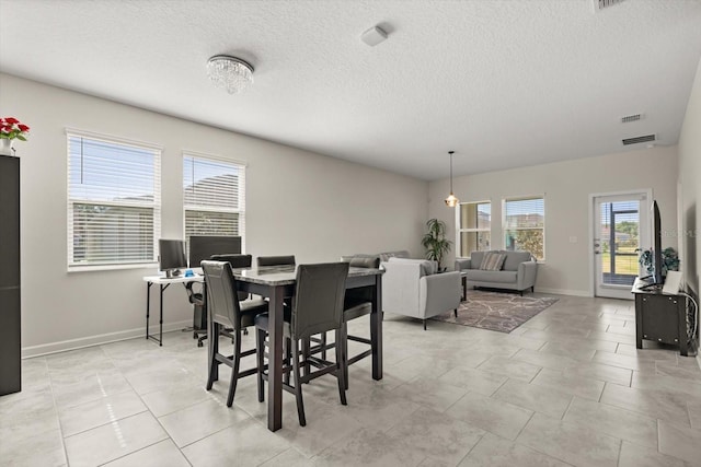 dining space featuring a textured ceiling, visible vents, and baseboards