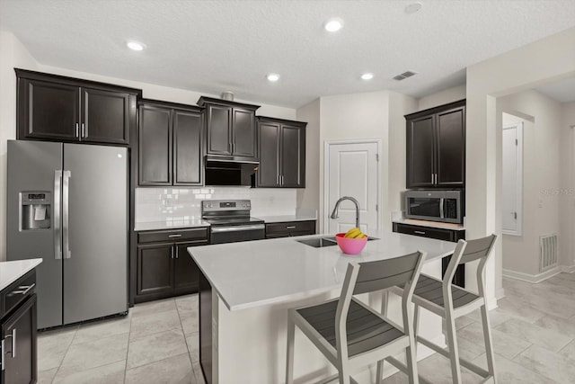 kitchen with a sink, visible vents, backsplash, light countertops, and appliances with stainless steel finishes