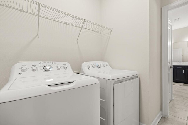 laundry area with baseboards, light tile patterned floors, and separate washer and dryer