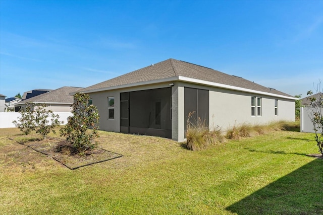 rear view of property featuring stucco siding, a yard, and a sunroom