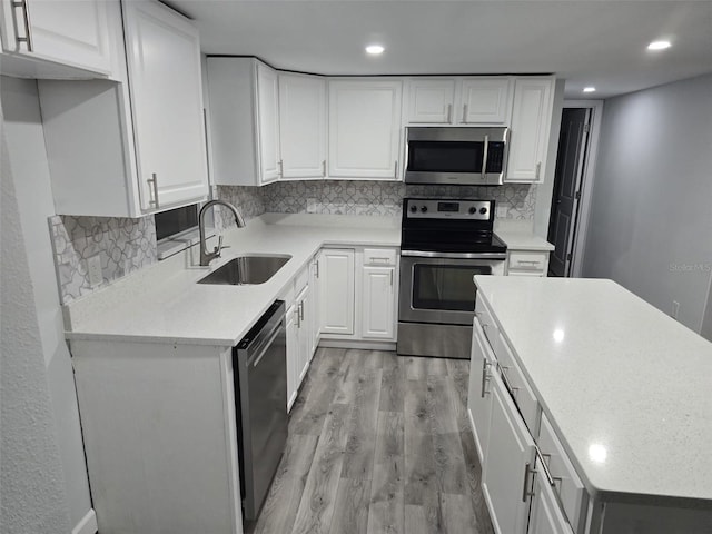 kitchen featuring backsplash, appliances with stainless steel finishes, a sink, and light wood finished floors