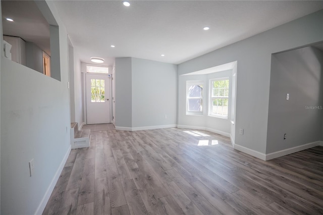 unfurnished living room featuring baseboards, plenty of natural light, and light wood-style flooring