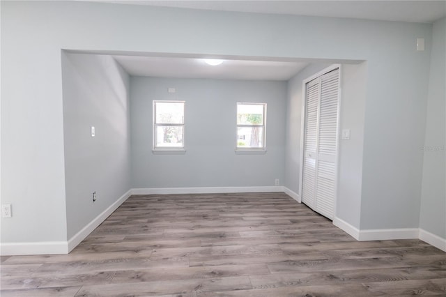 unfurnished bedroom with baseboards, wood finished floors, and a closet