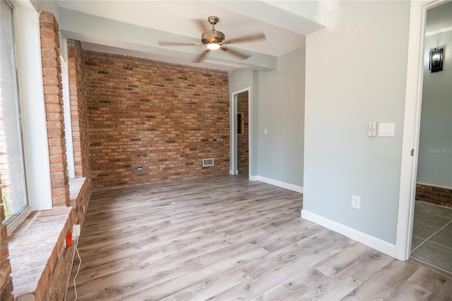 spare room with a ceiling fan, brick wall, and wood finished floors
