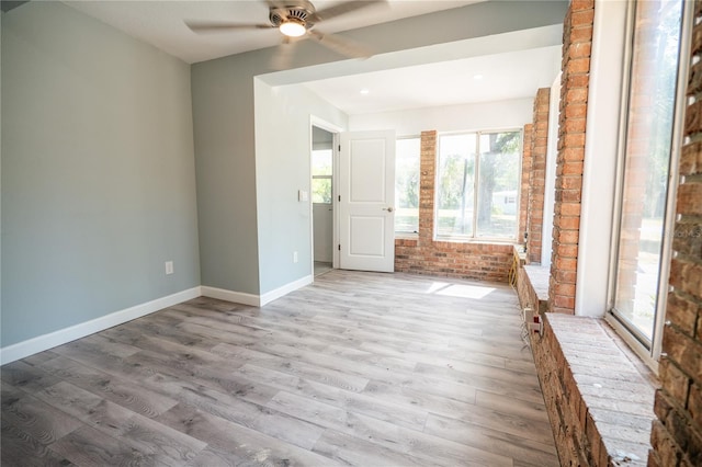 empty room with wood finished floors, brick wall, baseboards, ceiling fan, and recessed lighting
