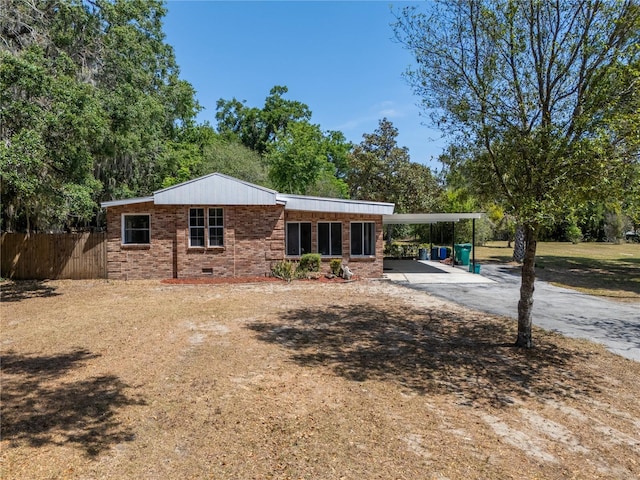 back of house with brick siding, fence, a carport, and aphalt driveway