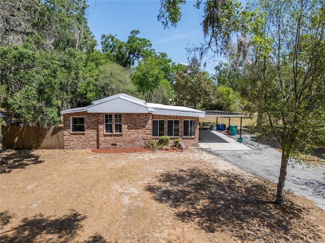 rear view of property featuring brick siding, fence, driveway, and a carport