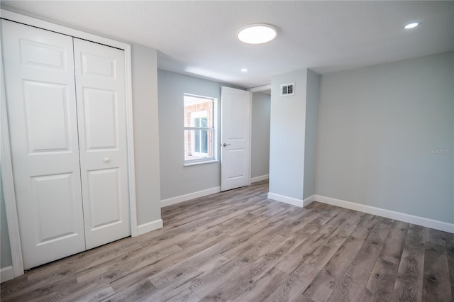 unfurnished bedroom featuring recessed lighting, baseboards, wood finished floors, visible vents, and a closet