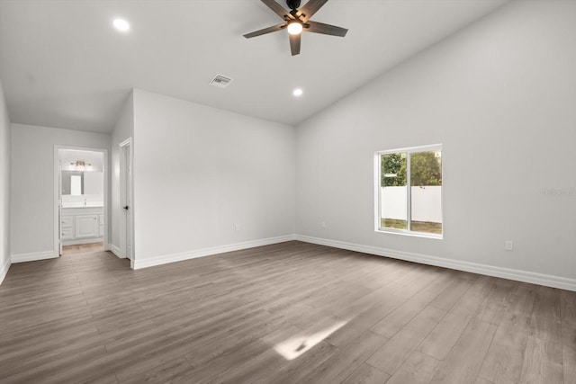 unfurnished bedroom with visible vents, ensuite bathroom, baseboards, dark wood-style flooring, and vaulted ceiling