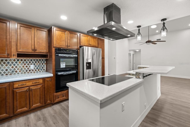 kitchen with island exhaust hood, ceiling fan, black appliances, light wood-style flooring, and baseboards