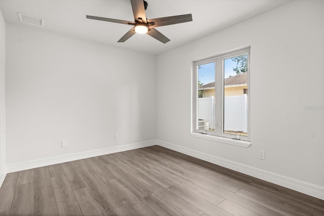 spare room with visible vents, ceiling fan, wood finished floors, and baseboards