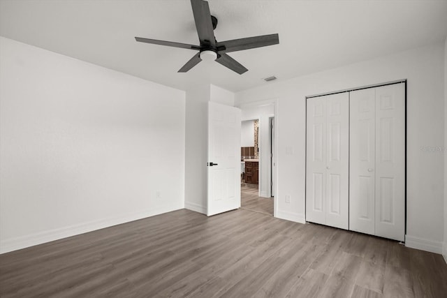 unfurnished bedroom with a closet, a ceiling fan, wood finished floors, and baseboards
