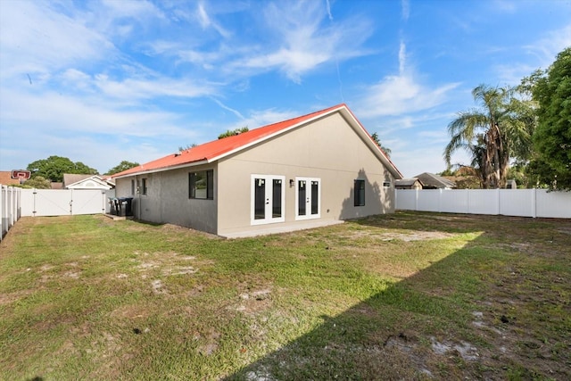 back of property featuring a gate, french doors, a fenced backyard, and a yard