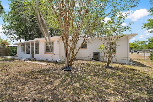 rear view of property featuring fence and central AC unit