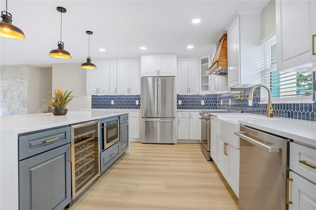 40 W Laurel St, Apopka, FL 32703 - kitchen with stainless steel appliances, light wood-style flooring, backsplash, white cabinetry, and beverage cooler
