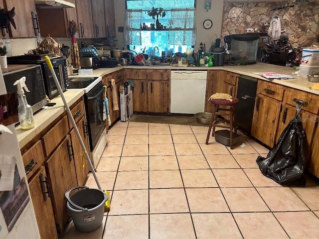 kitchen featuring electric range, dishwasher, light tile patterned floors, light countertops, and a sink