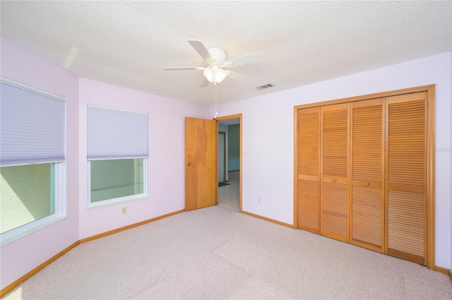 unfurnished bedroom featuring a ceiling fan, visible vents, baseboards, a closet, and carpet