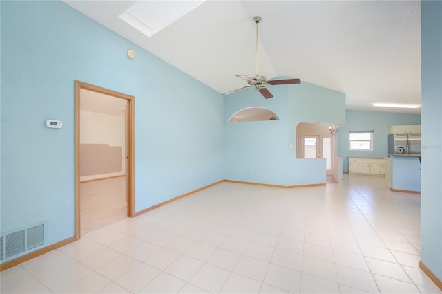 spare room with visible vents, a ceiling fan, baseboards, and lofted ceiling with skylight