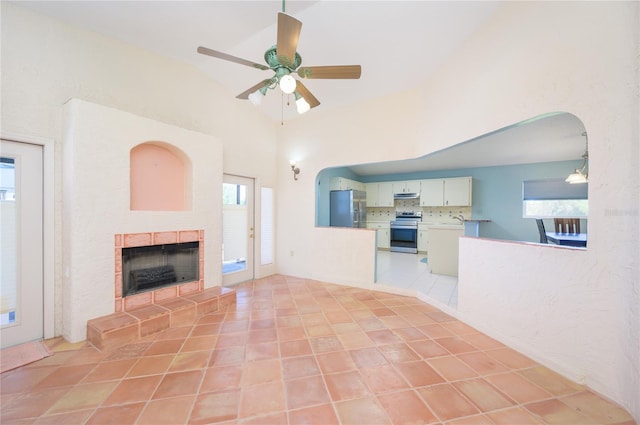 unfurnished living room featuring a tiled fireplace, ceiling fan, and a wealth of natural light