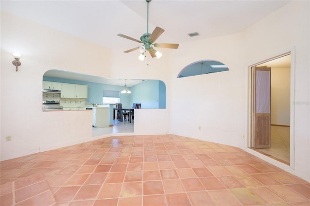 unfurnished living room with a ceiling fan, arched walkways, visible vents, and a towering ceiling