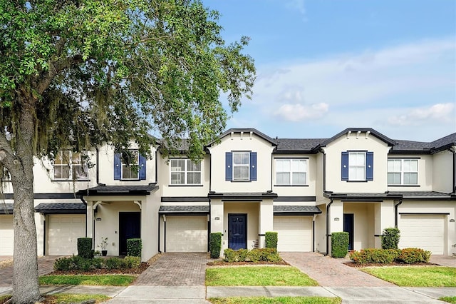 townhome / multi-family property with stucco siding, driveway, and an attached garage