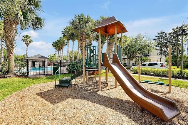 community jungle gym with fence and a community pool