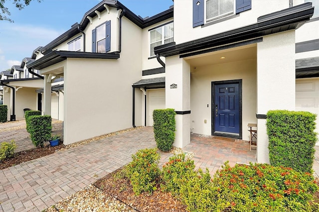 doorway to property featuring a garage and stucco siding