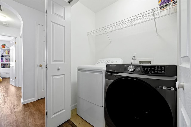 laundry area featuring baseboards, wood finished floors, separate washer and dryer, and laundry area
